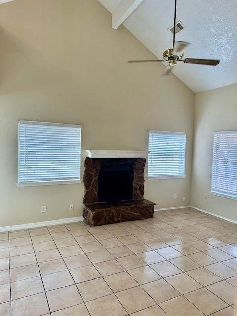 unfurnished living room with beam ceiling, a textured ceiling, light tile patterned floors, ceiling fan, and a fireplace