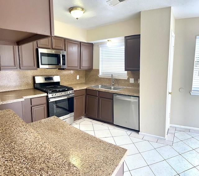 kitchen featuring sink, light tile patterned floors, stainless steel appliances, and backsplash