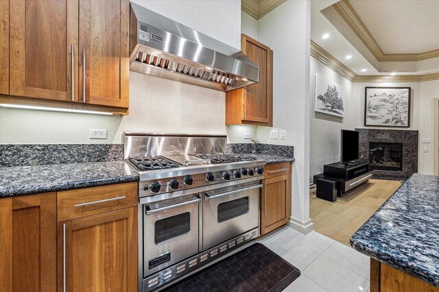 3388 Sage Rd Unit 2401, Houston, TX 77056 - kitchen featuring double oven range, wall chimney range hood, ornamental molding, dark stone countertops, and brown cabinets