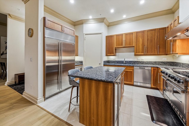 3388 Sage Rd Unit 2401, Houston, TX 77056 - kitchen with high quality appliances, a center island, ornamental molding, under cabinet range hood, and dark stone counters