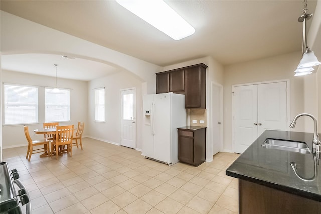 kitchen with dark brown cabinetry, sink, hanging light fixtures, and white fridge with ice dispenser