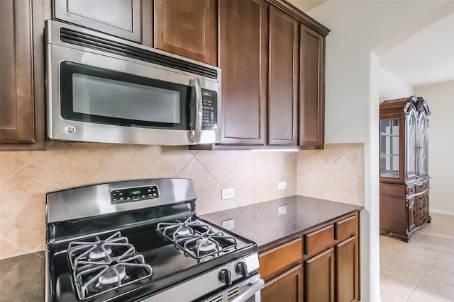 kitchen featuring backsplash, light tile patterned floors, and stainless steel appliances