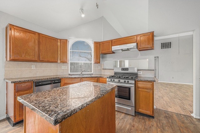 kitchen with appliances with stainless steel finishes, wood-type flooring, sink, and a kitchen island