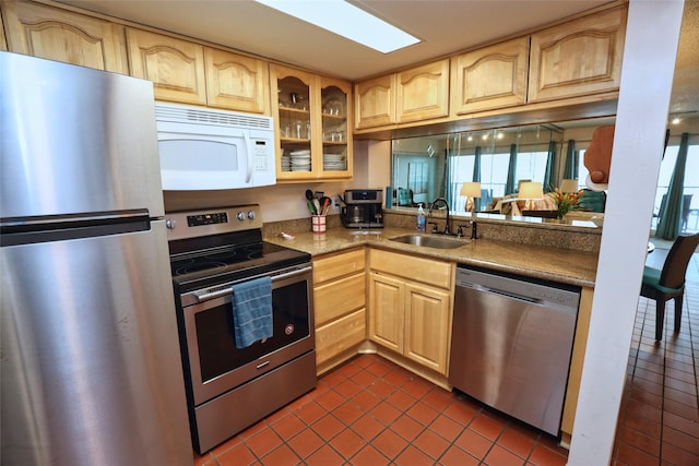 kitchen with dark tile patterned floors, appliances with stainless steel finishes, sink, and light brown cabinetry