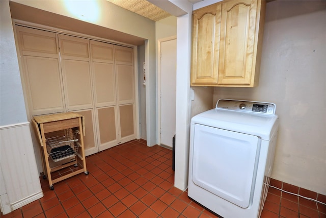 clothes washing area with washer / clothes dryer and cabinets