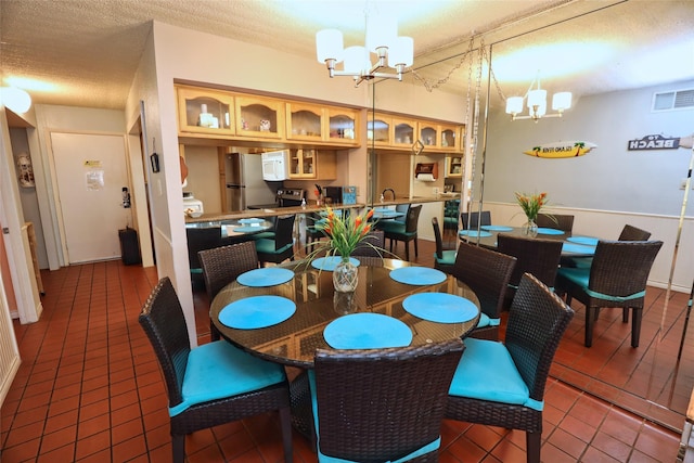 dining room with tile patterned flooring, a textured ceiling, and a notable chandelier