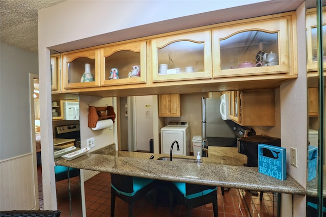 kitchen featuring washer / clothes dryer, sink, a breakfast bar area, tile patterned floors, and a textured ceiling