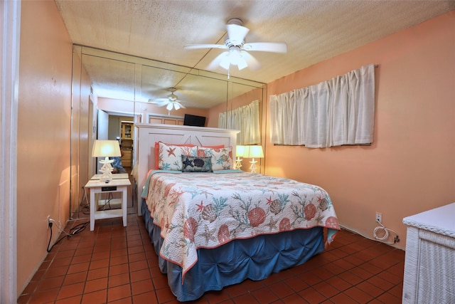 bedroom featuring ceiling fan, dark tile patterned flooring, and a textured ceiling