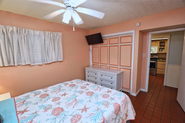 bedroom featuring dark tile patterned flooring, a closet, a textured ceiling, and ceiling fan