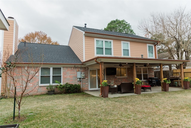 back of property with ceiling fan, an outdoor living space, a patio area, and a lawn