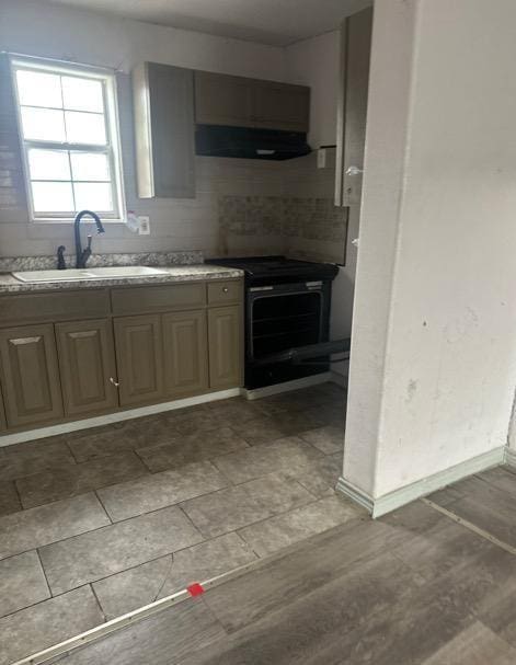 kitchen featuring black electric range oven, backsplash, ventilation hood, and sink