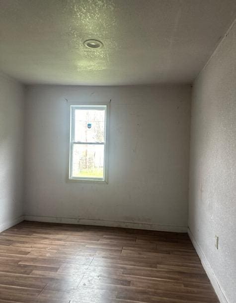 unfurnished room with hardwood / wood-style floors and a textured ceiling