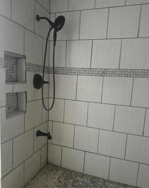 details with a tile shower and a package area