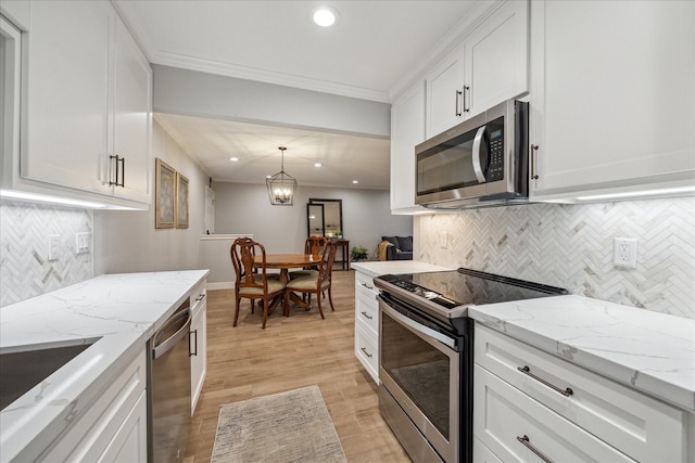 kitchen featuring white cabinetry, stainless steel appliances, decorative light fixtures, and light stone counters