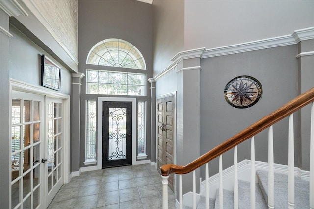 tiled foyer featuring stairway, french doors, a towering ceiling, and baseboards