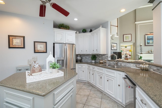 kitchen with stainless steel appliances, a sink, white cabinetry, and decorative backsplash