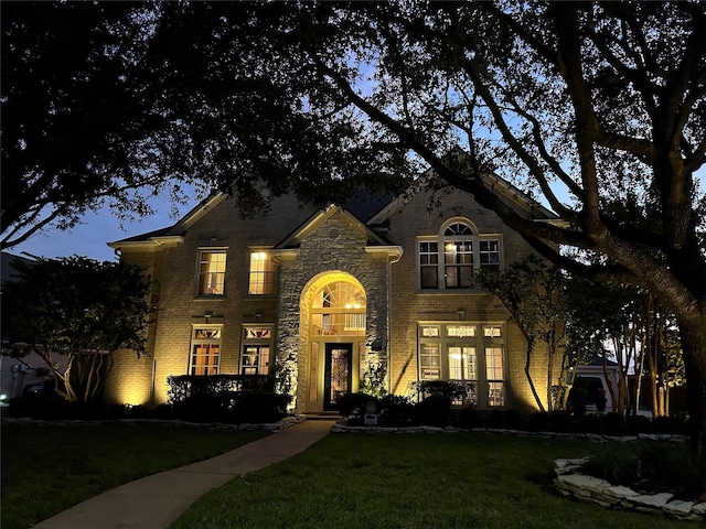 view of front of house with stone siding, brick siding, and a front yard