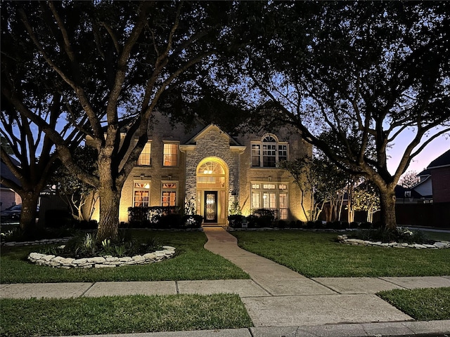 french country inspired facade with stone siding, brick siding, and a yard