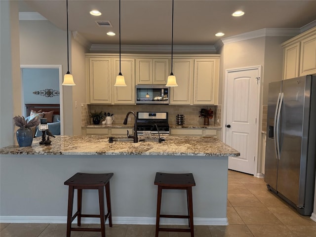 kitchen featuring appliances with stainless steel finishes, hanging light fixtures, ornamental molding, light stone countertops, and cream cabinetry