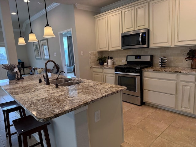 kitchen with sink, light stone counters, decorative light fixtures, an island with sink, and stainless steel appliances