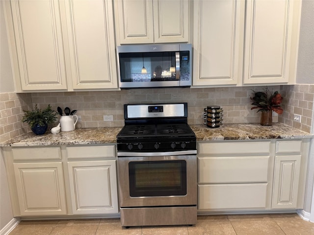 kitchen featuring light stone counters, stainless steel appliances, tasteful backsplash, and light tile patterned floors