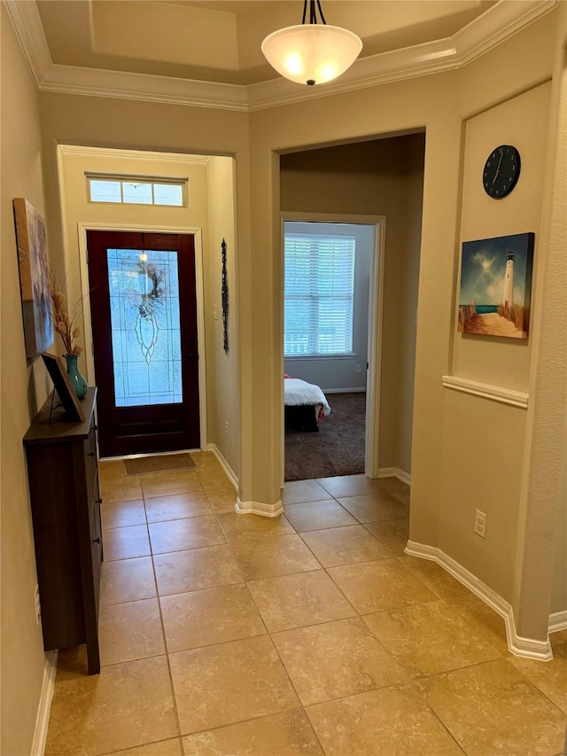 entryway featuring a tray ceiling, light tile patterned floors, and crown molding