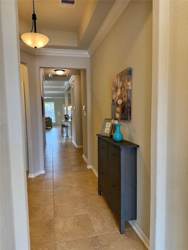 corridor with a raised ceiling, crown molding, and light tile patterned floors