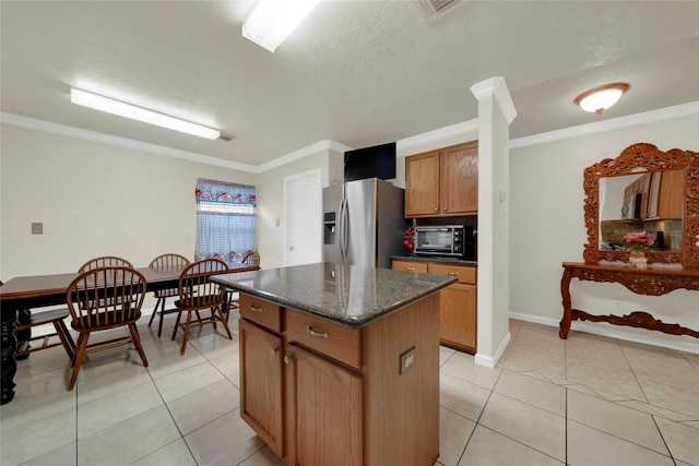 kitchen with ornamental molding, a center island, light tile patterned floors, and stainless steel fridge