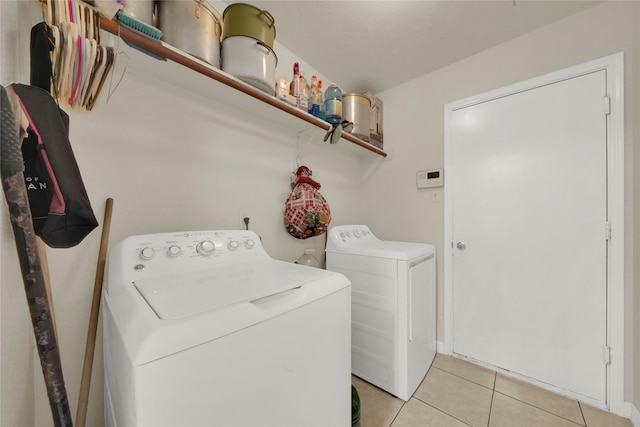 clothes washing area featuring washer and clothes dryer and light tile patterned floors