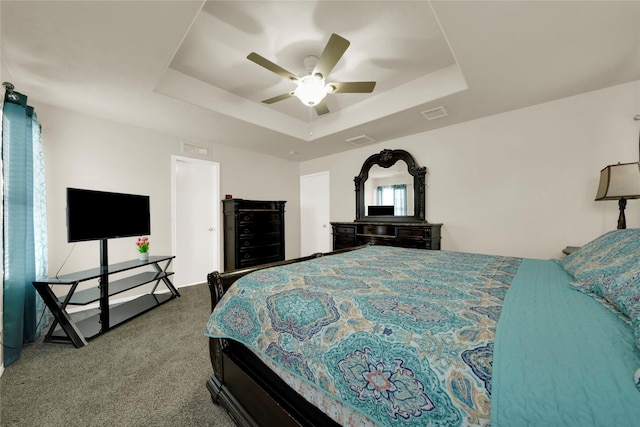 carpeted bedroom featuring ceiling fan and a tray ceiling