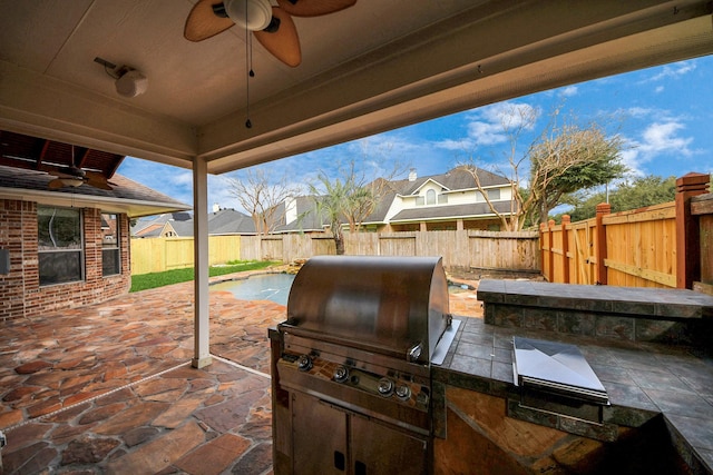 view of patio featuring a ceiling fan, a fenced backyard, and an outdoor kitchen