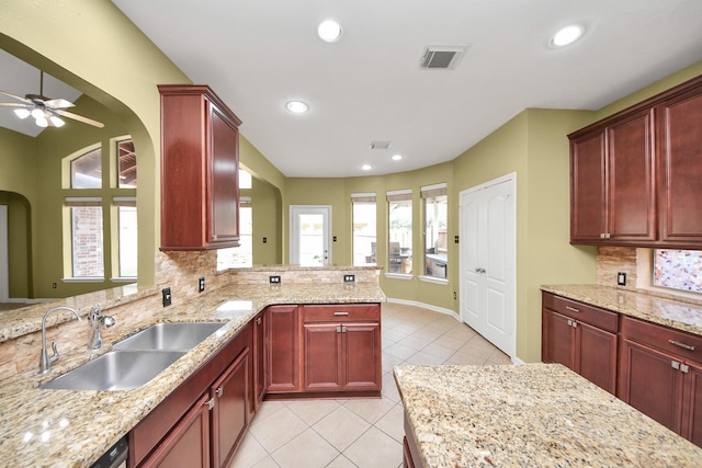 kitchen with light tile patterned floors, dark brown cabinets, arched walkways, and a sink