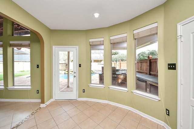 entryway with light tile patterned floors, baseboards, and arched walkways