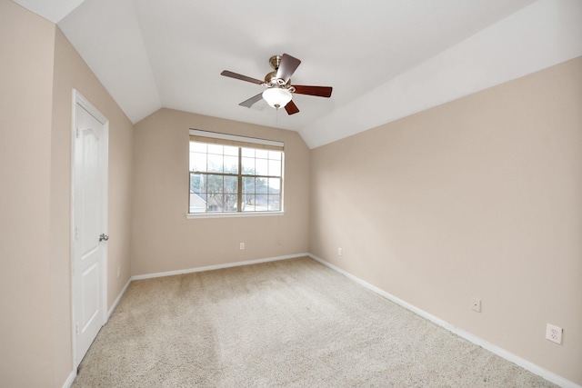 empty room with vaulted ceiling, carpet floors, a ceiling fan, and baseboards