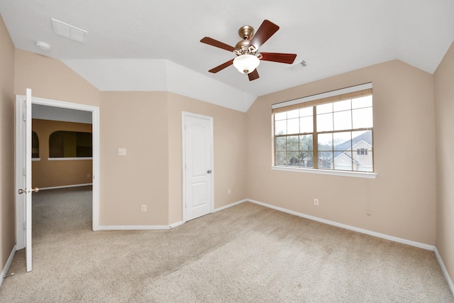 spare room with vaulted ceiling, carpet floors, visible vents, and baseboards