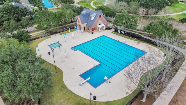 community pool featuring fence, a diving board, and a patio