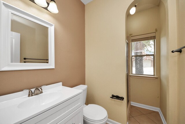 bathroom with toilet, tile patterned flooring, baseboards, and vanity