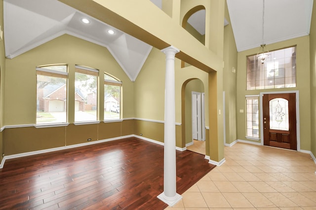 foyer featuring high vaulted ceiling, decorative columns, a wealth of natural light, and baseboards