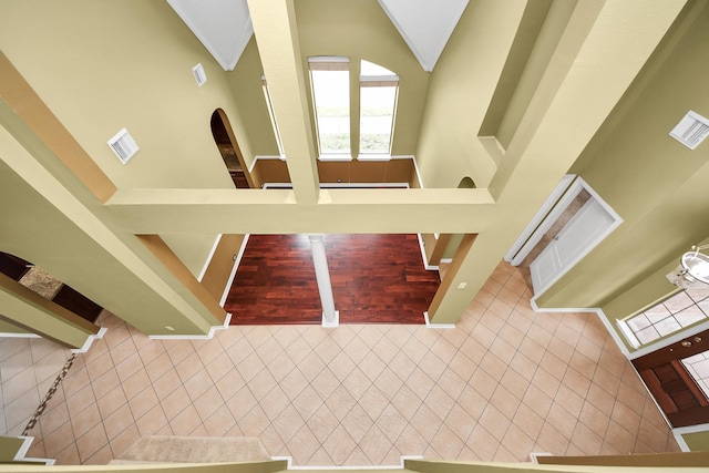 tiled foyer featuring high vaulted ceiling, visible vents, and stairway