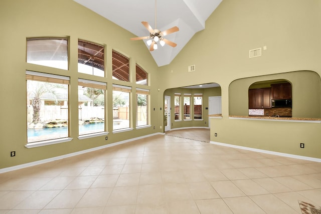 unfurnished living room featuring arched walkways, light tile patterned floors, visible vents, ceiling fan, and baseboards