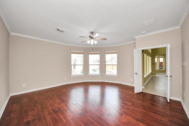 empty room with dark wood-style floors, crown molding, visible vents, and baseboards