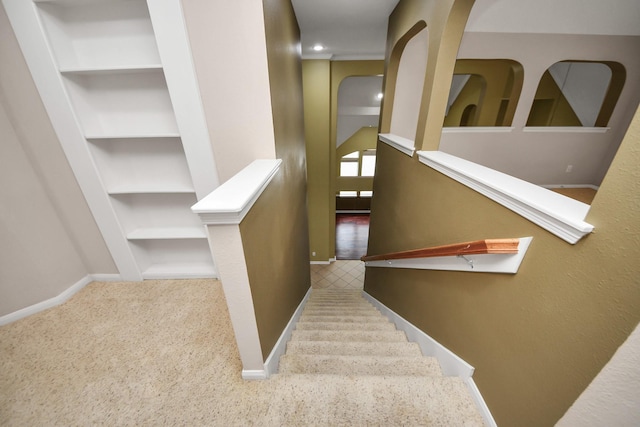 stairway featuring built in shelves, carpet, and baseboards