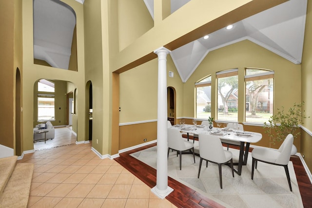 dining area with arched walkways, high vaulted ceiling, light tile patterned flooring, recessed lighting, and baseboards