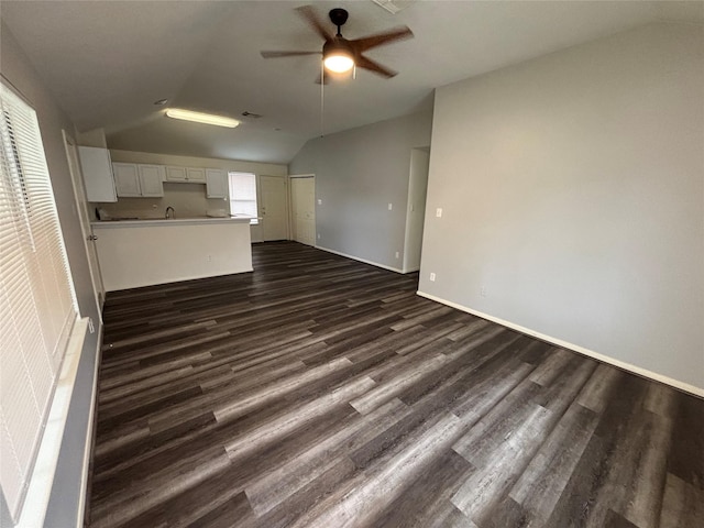 unfurnished living room with dark hardwood / wood-style flooring, vaulted ceiling, and ceiling fan