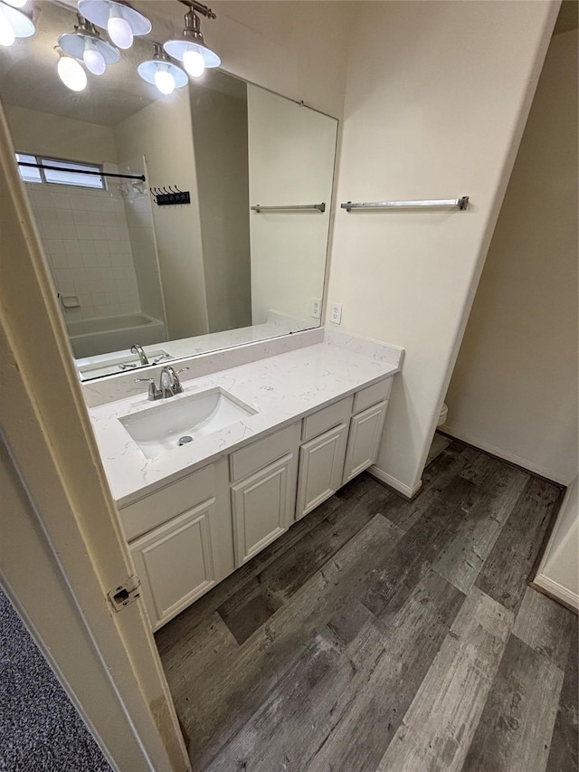 bathroom with washtub / shower combination, wood-type flooring, and vanity