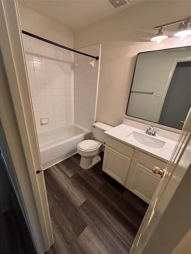 full bathroom featuring vanity, tiled shower / bath, wood-type flooring, and toilet