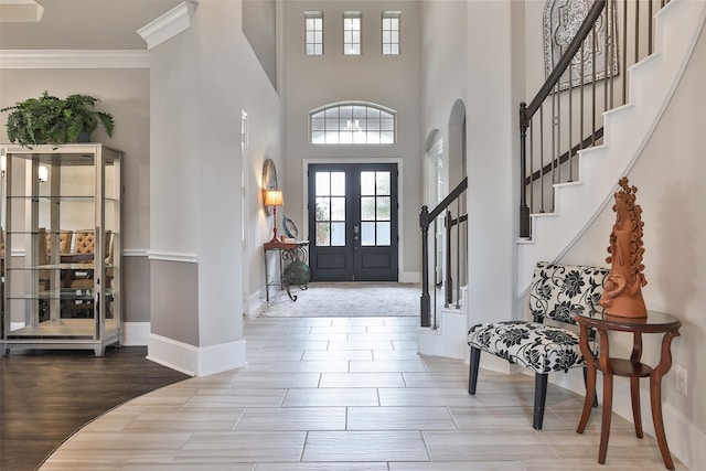 entryway with french doors, crown molding, a high ceiling, and hardwood / wood-style flooring