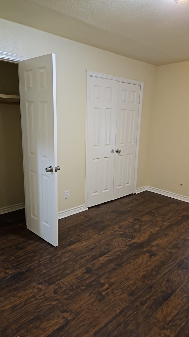 unfurnished bedroom with a textured ceiling, dark hardwood / wood-style flooring, and a closet