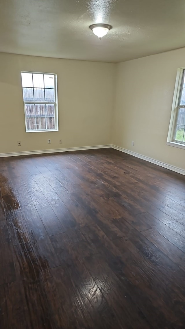 empty room with a textured ceiling and dark hardwood / wood-style flooring