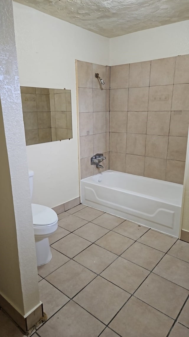 bathroom featuring tiled shower / bath, tile patterned floors, a textured ceiling, and toilet